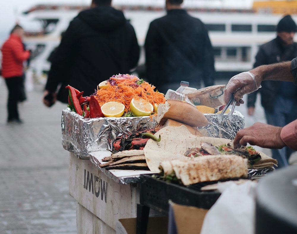 LA street food stall with wraps, vegetables, and people in the background