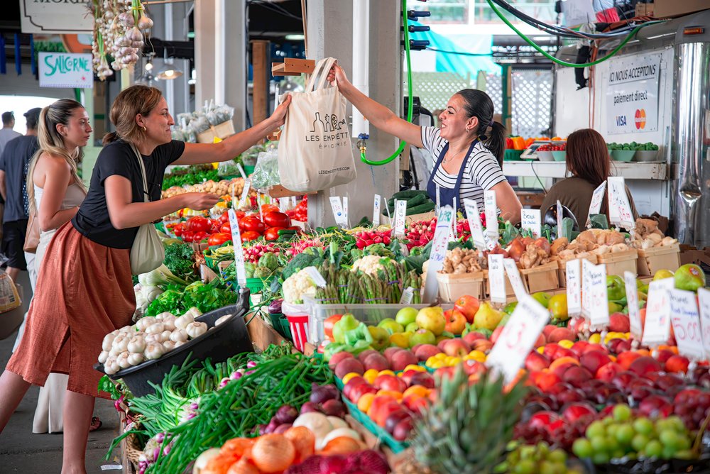 Vendor handing produce to customer at Los Angeles farmers market