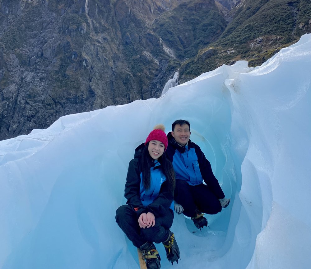 Couple exploring blue glacier ice formations near Mount Cook from Queenstown tour