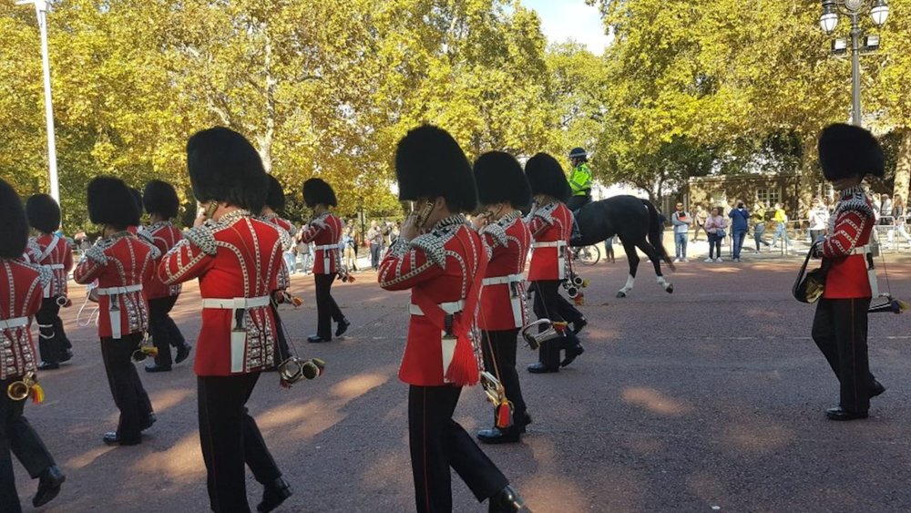 British guards in red uniforms and bearskin hats marching during the Changing of the Guard in London