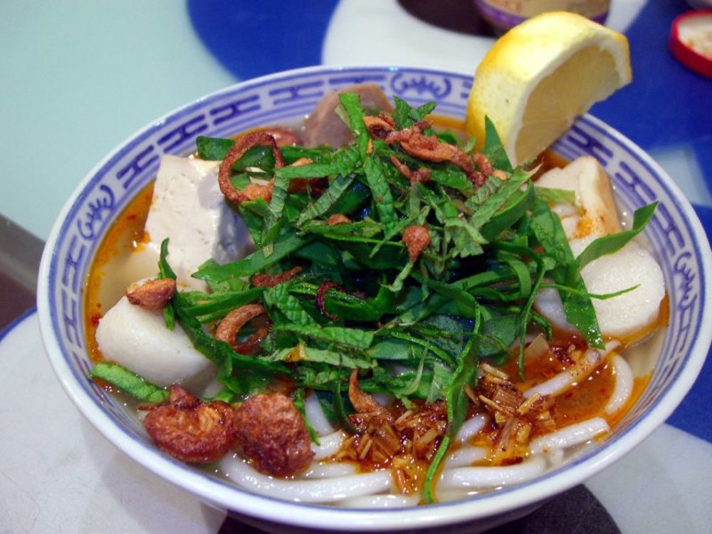Bowl of Bun Bo Hue with beef, noodles, herbs, and chili oil broth