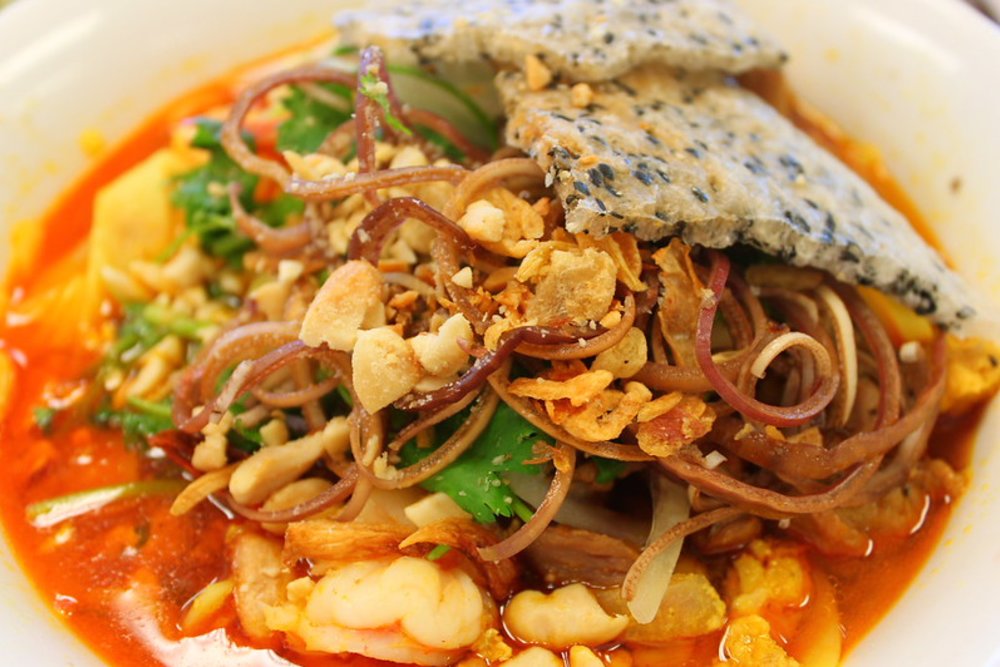 Mi Quang noodles topped with shrimp, pork, herbs, and crispy rice crackers