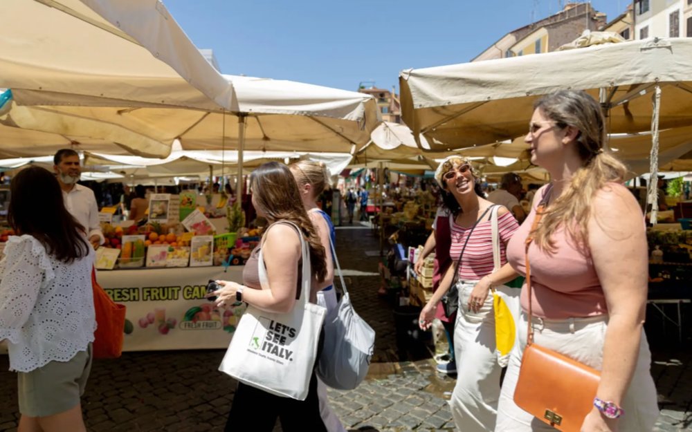Five women walking and talking in an outdoor market