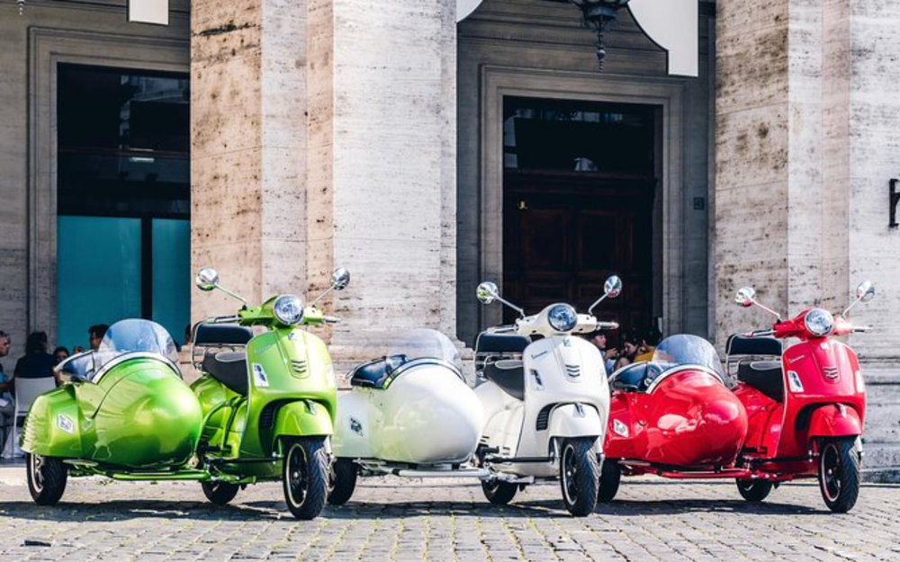 Green, white, and red motorcycles side by side in front of the building.