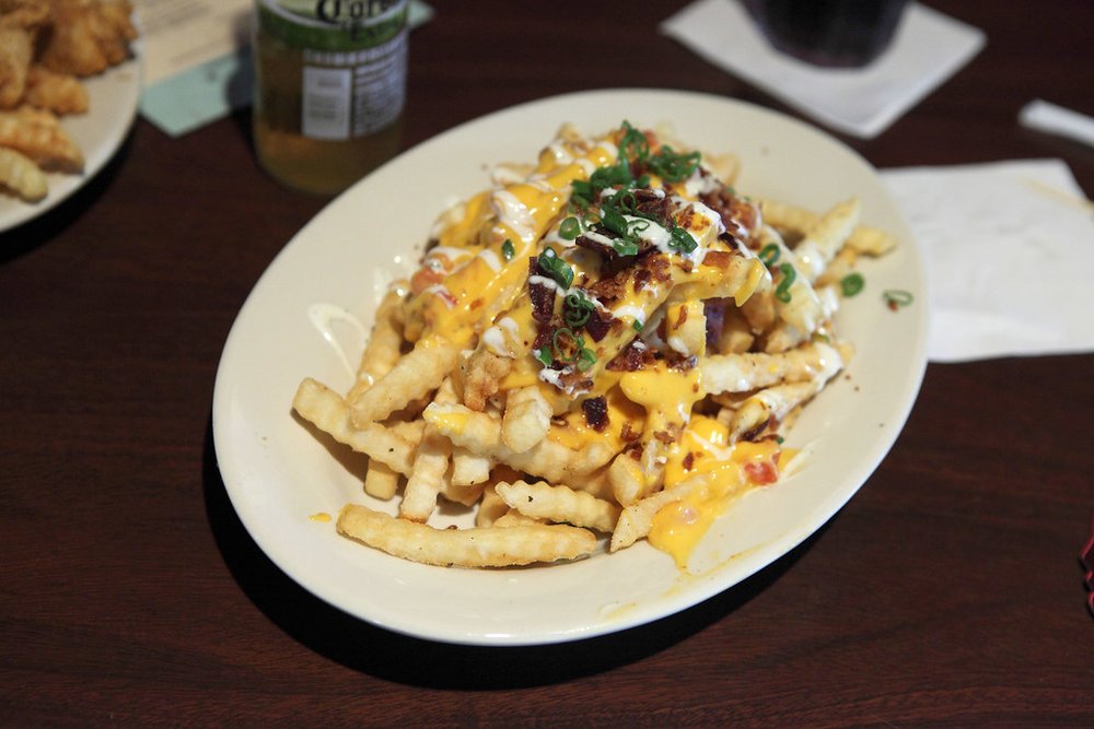 Loaded fries topped with cheese, bacon, and green onions | Photo Credit: Flickr