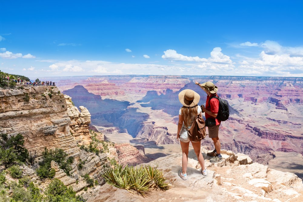 Tourists overlooking Grand Canyon cliffs and Colorado River below