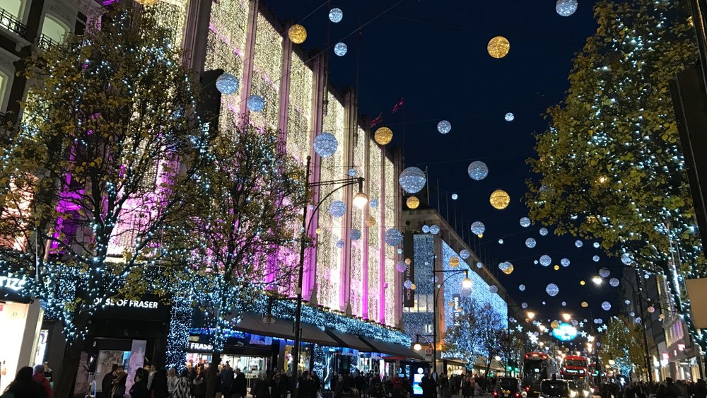 Oxford Street lit up at night with festive lights and busy London crowds