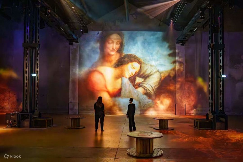 Travelers admiring paintings at Atelier des Lumieres in Paris.