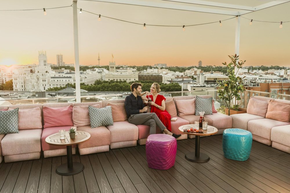 A couple sitting on a rooftop with Madrid in the background