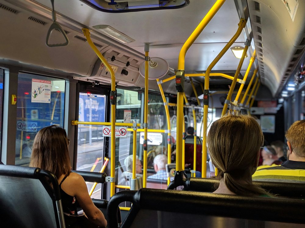 A view of the inside of a bus and passengers heads from the backseat.