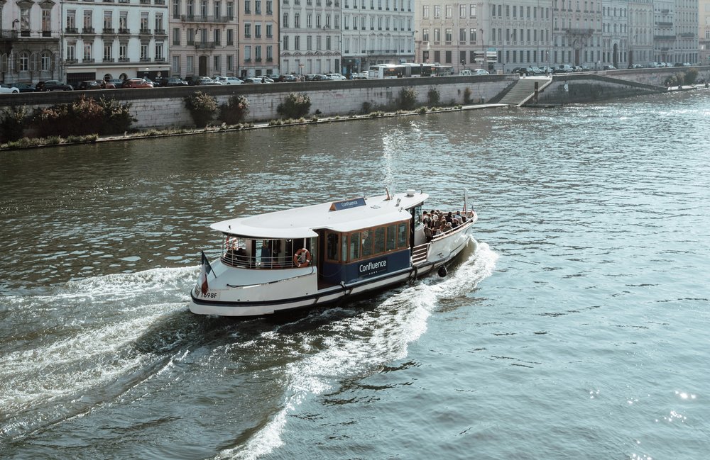 A medium-sized boat full of passengers sailing along a river