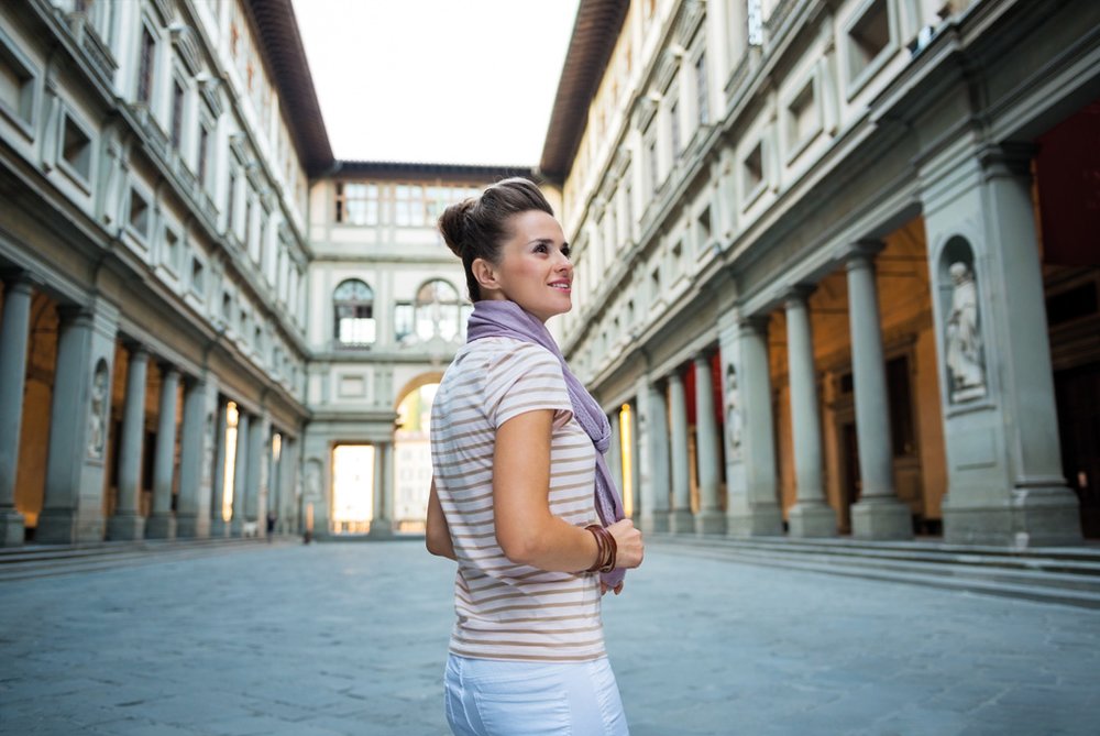 Visitor walking inside Uffizi Gallery corridor surrounded by Renaissance architecture
