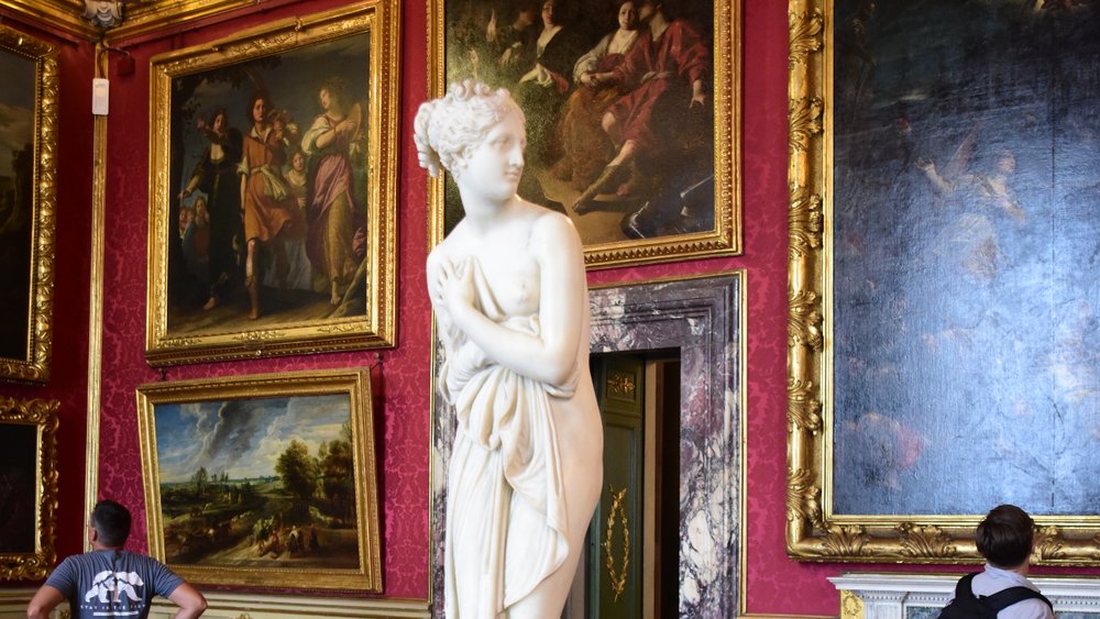 Interior of Pitti Palace with classical statue and Renaissance paintings on display