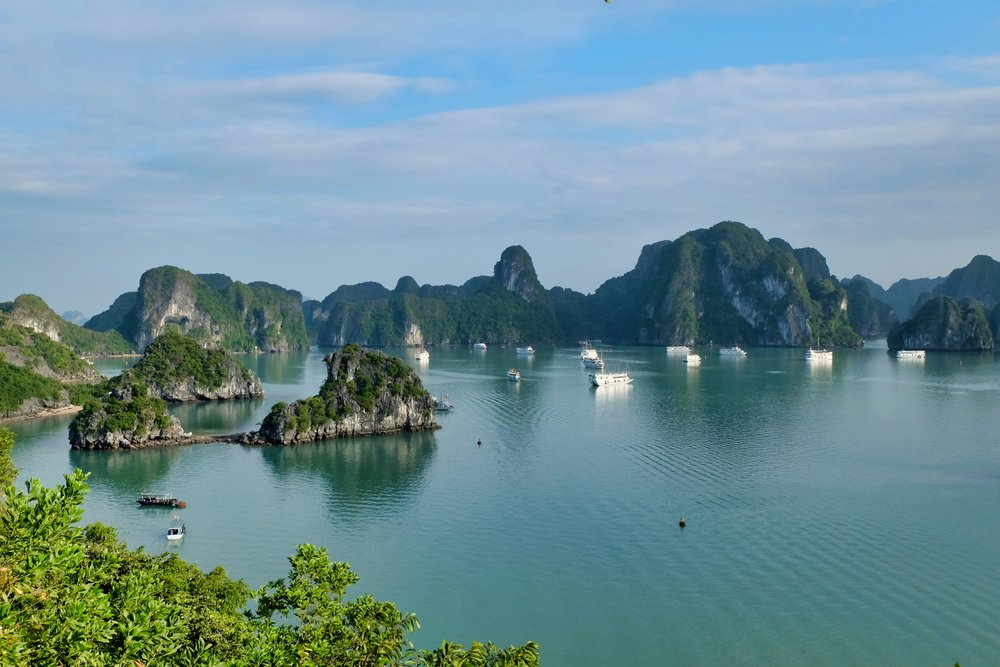 Large grey mountains behind a large body of water with floating boats