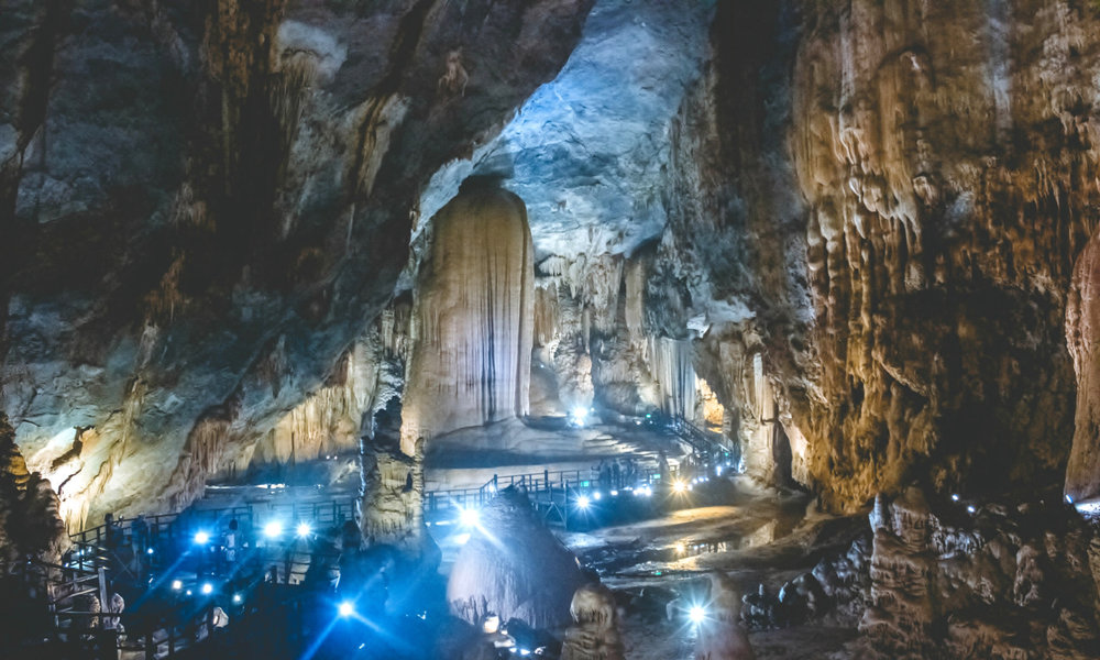 The inside of a large cave with numerous lights illuminating it