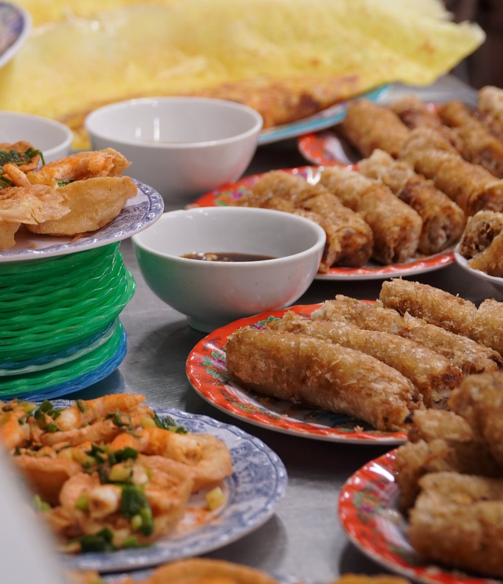 Plates and bowls full of fried rolls and shrimp covering a table.