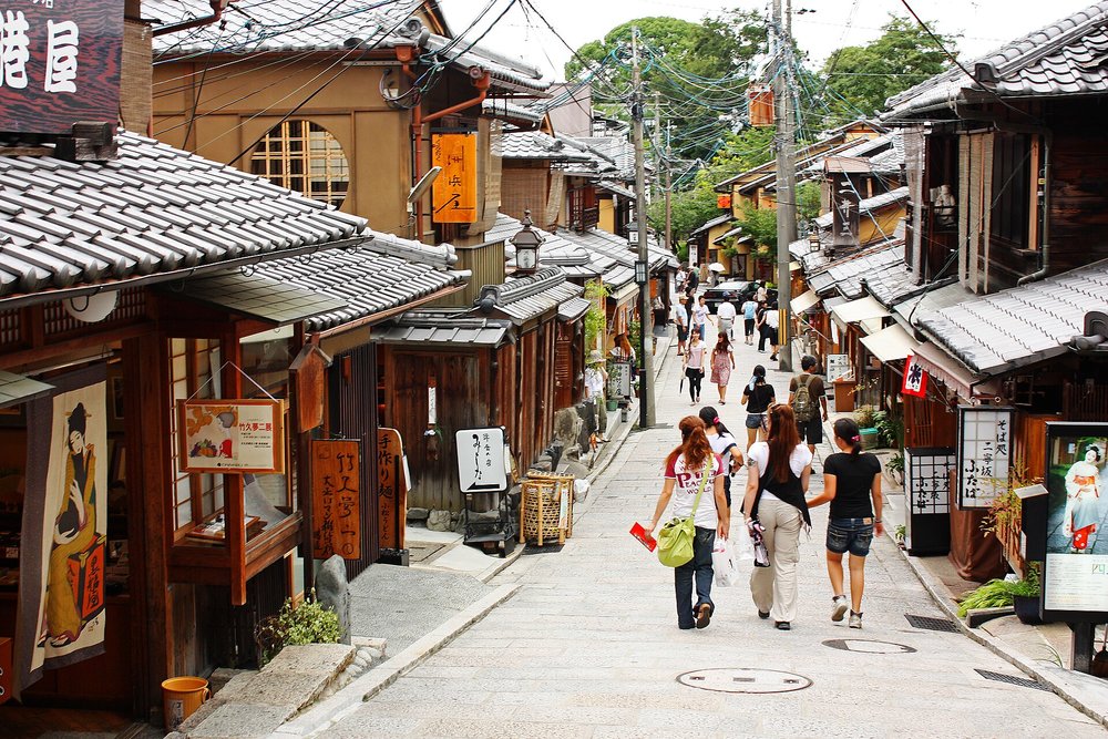 People walking along rows of traditional wooden houses