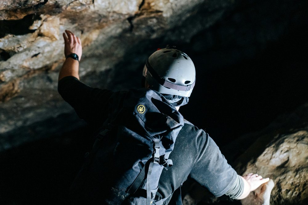 A person holding onto rocks inside a cave.