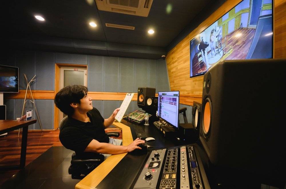 Person recording song in K-pop studio with mixing equipment in Seoul