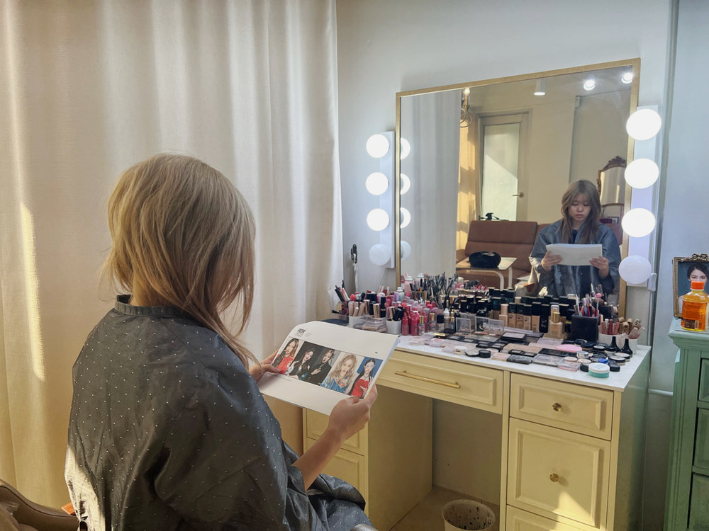 Person reviewing K-pop idol look before makeup session in studio