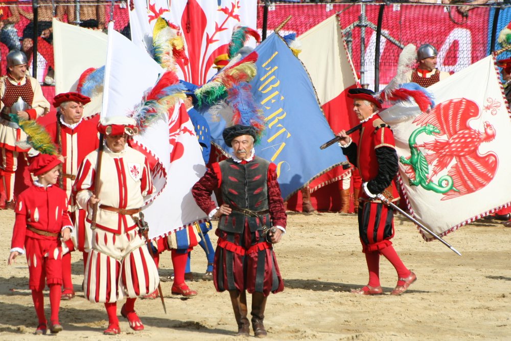 Players in 16th-century historical costumes grappling on a sand-covered field in Piazza Santa Croce