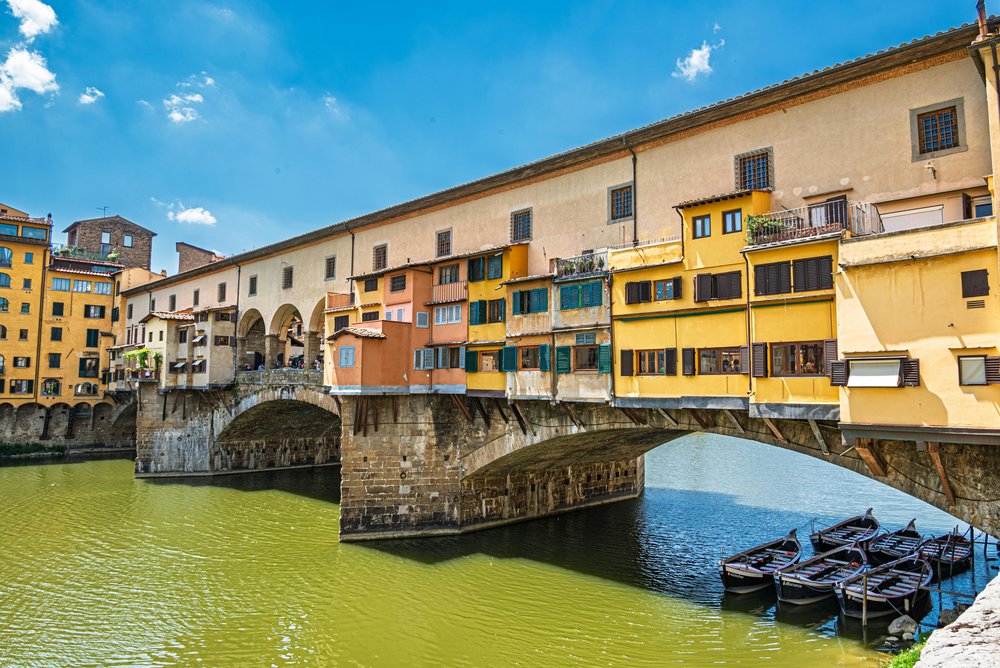 The Ponte Vecchio bridge lined with shops crosses the Arno River in Florence during sunset