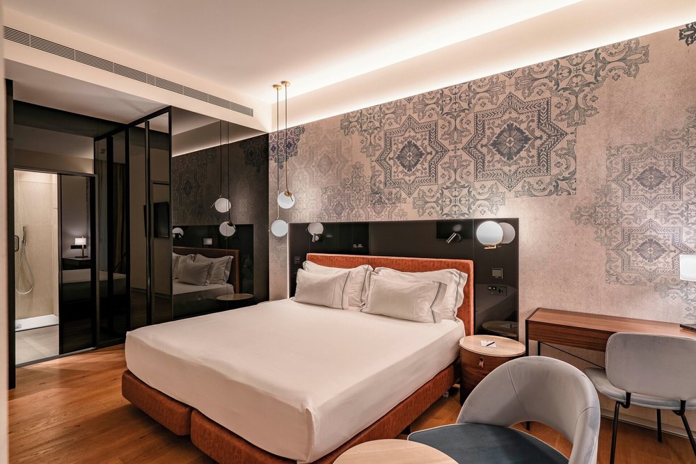Modern hotel room at Vincci Selección Unuk with patterned wall design, plush bed, and sleek lighting accents