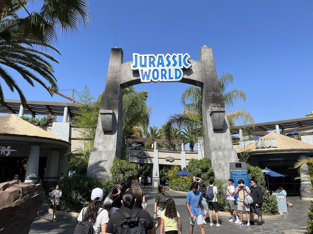 A few people at the entrance to Jurassic World