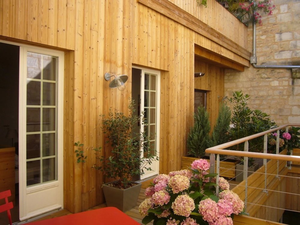 Courtyard terrace at L'Esprit des Chartrons with wooden exterior and blooming flowers
