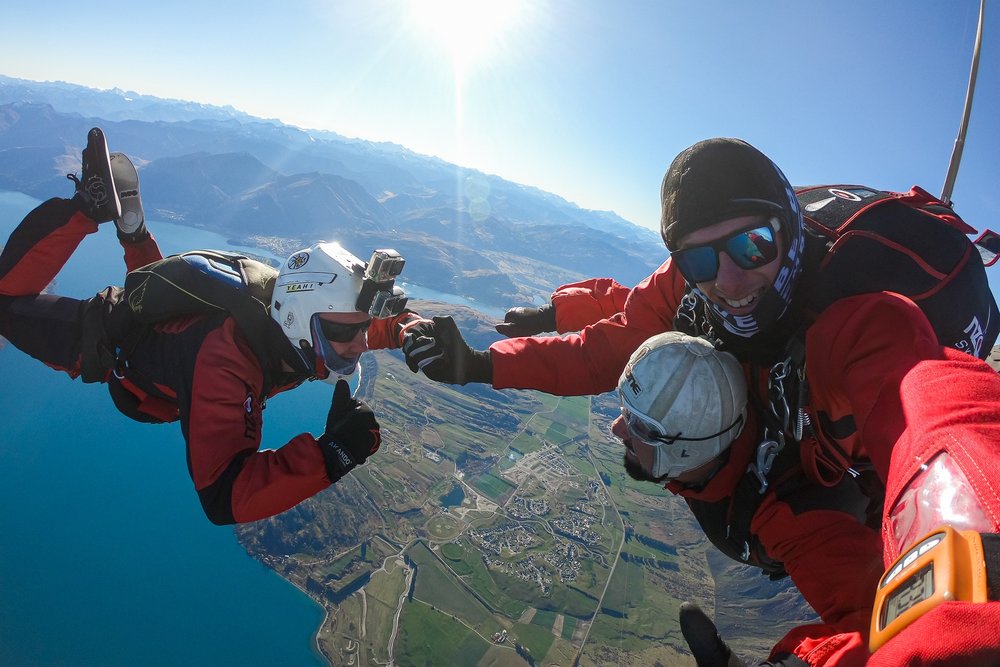 A man skydiving above Queenstown with two instructors.