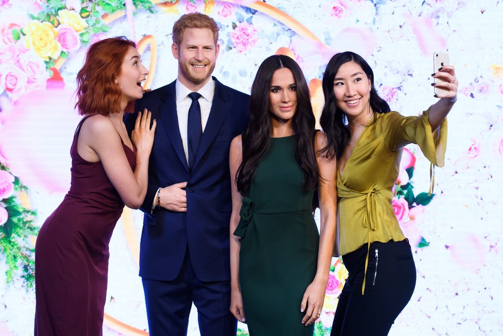 Visitors taking a selfie with wax figures of Prince Harry and Meghan Markle at Madame Tussauds London
