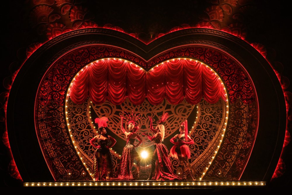 Performers on stage in red costumes during a vibrant Moulin Rouge musical performance