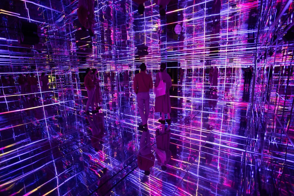 Visitors inside a neon-lit mirrored room at MOCO Museum London