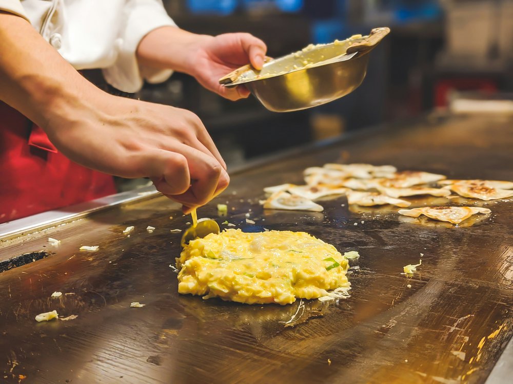 Cooking okonomiyaki in front of diners