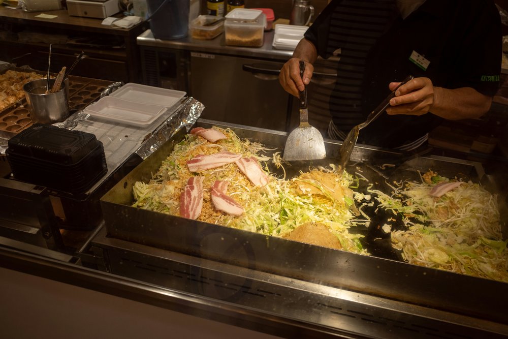 Chef cooking okonomiyaki in a Teppan