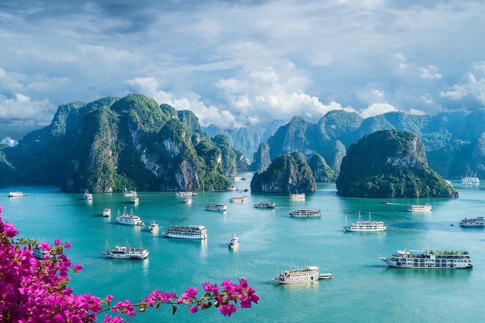 Majestic limestone karst islands rise dramatically from the calm green waters of Ha Long Bay in North Vietnam.