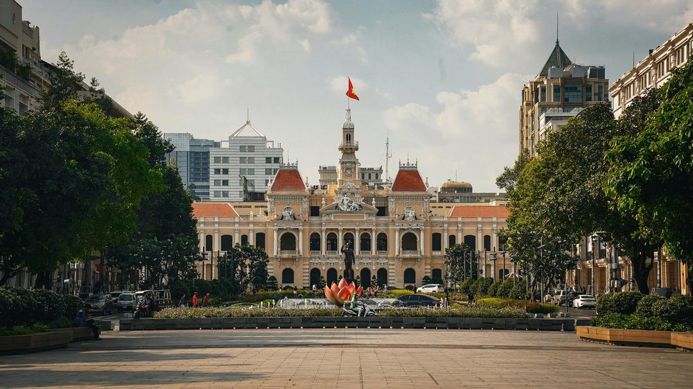 Ho Chi Minh City Hall (HCMC People's Committee Building) at sunset, surrounded by busy city streets.
