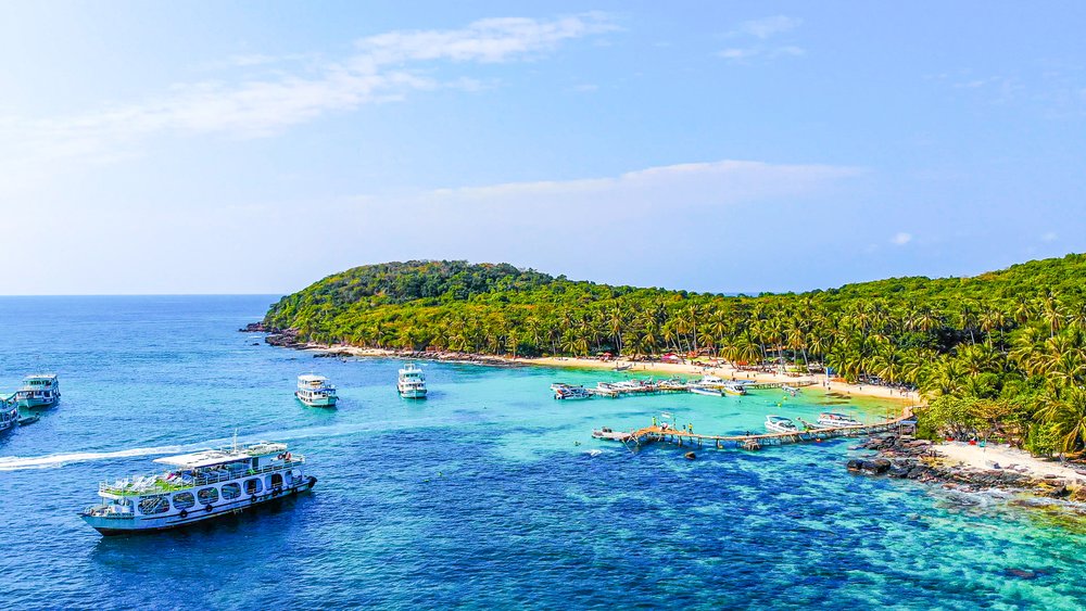 A pristine white-sand beach on Phu Quoc island with palm trees and a clear turquoise ocean.
