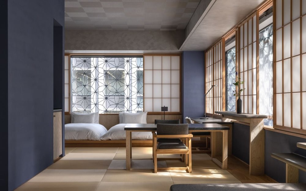 Two beds and a table and chair set inside a hotel room