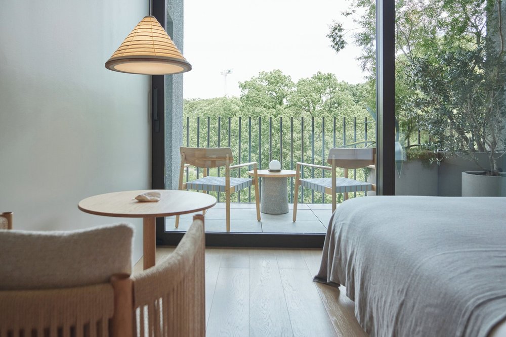 A floor-to-ceiling window leading to a balcony with two chairs and a coffee table