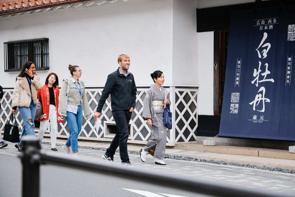 A group of travelers exploring Saijo Sake Brewery Street in Hiroshima