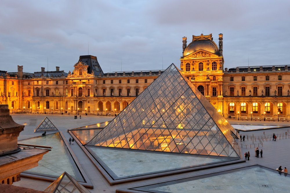 The Louvre Museum glowing at dusk in Paris