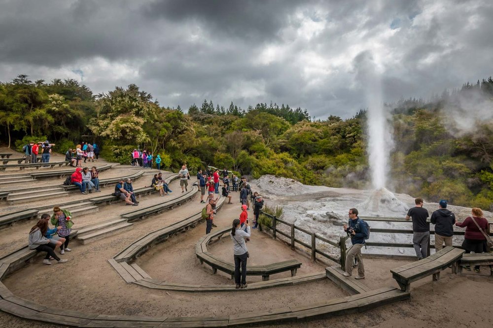 Visitors watching a geyser erupt in Rotorua geothermal park