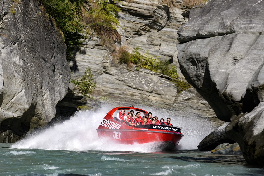 Red Shotover Jet speeding through a narrow rocky canyon near Queenstown