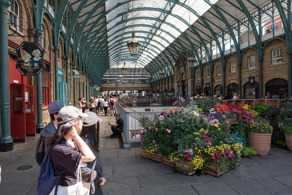 Flowers in London’s Covent Garden Market, with tourists enjoying a sunny day
