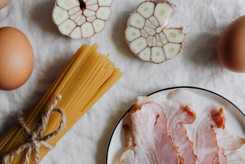 Ingredients for classic carbonara: pasta, bacon, eggs, garlic