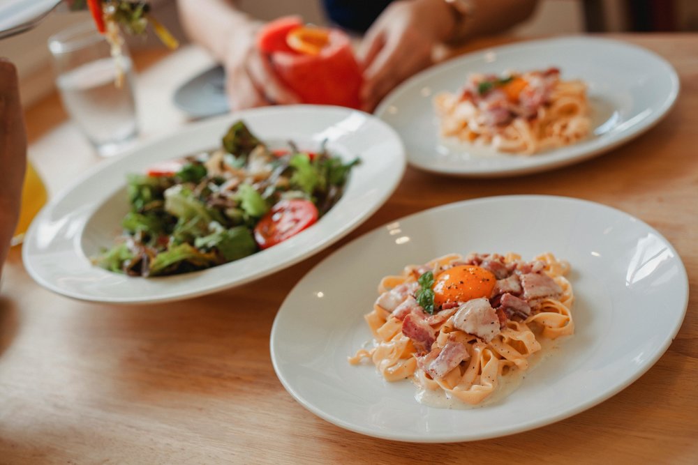 Indulge in a classic carbonara with bacon and egg, served with a crisp green salad