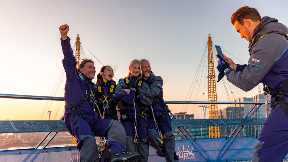 Visitors celebrate during the Up at The O2 rooftop climb experience in London