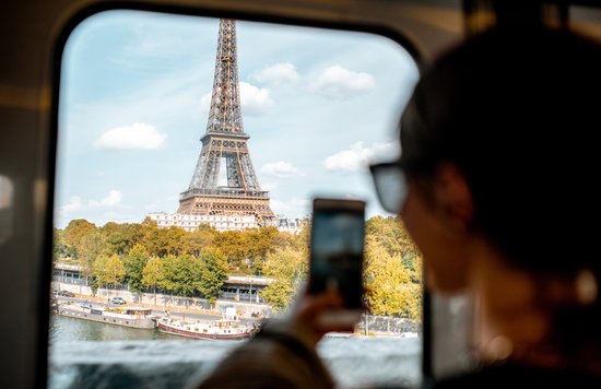 woman taking a photo of the eiffel tower from a train window