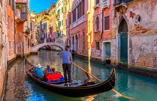 Gondola ride under bridge in vibrant Venice canal with gondolier and passengers
